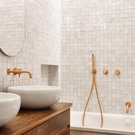 White terracotta tiles cover bathroom walls, arranged in a grid pattern, complementing wooden and ceramic bathroom fixtures.