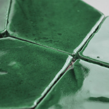 Les carreaux de terre cuite verte, joints et brillants, forment un motif texturé, capturant la lumière dans un décor intérieur r