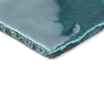 A glazed, green terracotta tile showing dripping texture. resting on a white background, highlighting its glossy surface and une