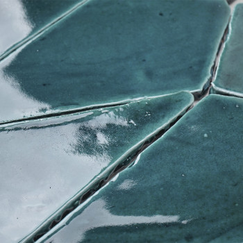 Glazed blue-green terracotta tiles fit together, forming an uneven, reflective surface with visible grout lines.