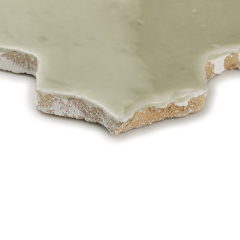 Los azulejos de terracota de bordes rugosos muestran un esmalte verde que resalta la textura sobre un fondo blanco simple.