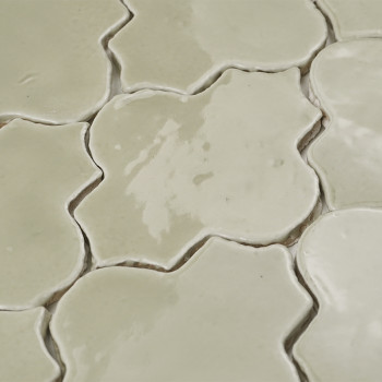 Los azulejos de terracota de color crema forman un patrón floral, con superficies brillantes que reflejan la luz en una disposic