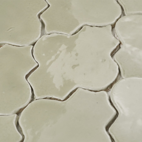 Los azulejos de terracota de color crema forman un patrón floral, con superficies brillantes que reflejan la luz en una disposic