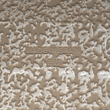 De keramische tegel heeft een gestructureerd, onregelmatig patroon met verhoogde beige en witte vlakken. De tekst luidt MADE IN 