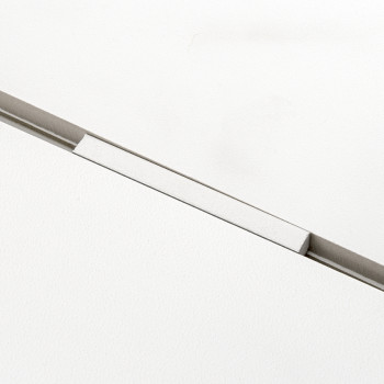 Een witte tegel met een smalle, verzonken rechthoekige groef die hem diagonaal doorsnijdt, waardoor een strakke, minimalistische