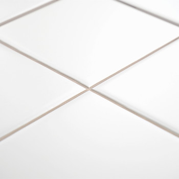 White ceramic tiles with a glossy finish form a grid pattern, joined by thin grout lines, in a bright, clean environment.