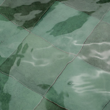 Groene keramische tegels, gedeeltelijk ondergedompeld, reflecteren licht en water en creëren een golvend, rustig effect in een w