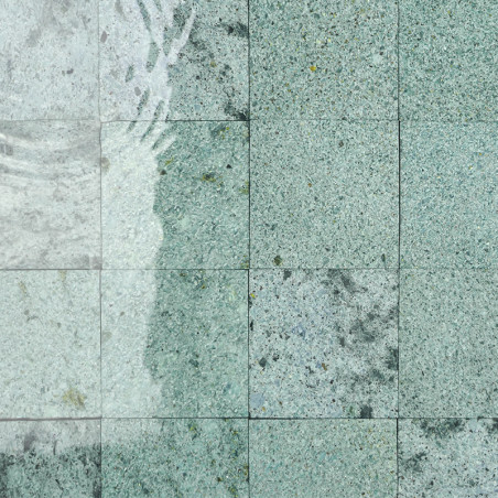 Stone tiles display a subtle speckled pattern, partially submerged, with water casting gentle ripples over their surface.