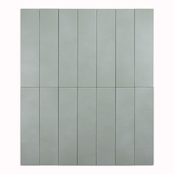 Un azulejo largo, rectangular y de color verde claro se alza sobre un fondo blanco liso, resaltando la textura de su superficie 