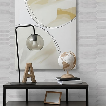 Auf einem kleinen Tisch stehen ein Holzbuchstabe „A“, eine moderne Lampe mit Glaskugel und eine Deko-Weltkugel. Darüber hängt ei