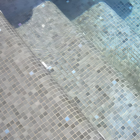 Glass tiles form steps submerged in water, creating a shimmering pattern under clear, gently moving pool water.