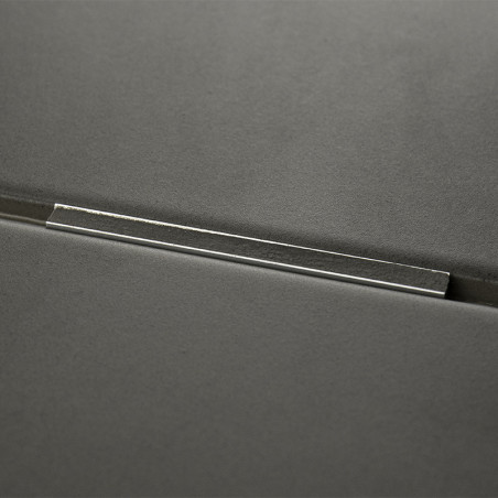 Een donkergrijze tegel met een metalen staaf over het oppervlak, die licht reflecteert, tegen een gladde, minimalistische achter