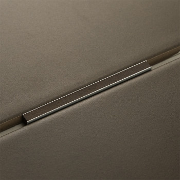 A metal trim rests between two matte gray tiles, forming a precise seam in a modern, minimalistic design.