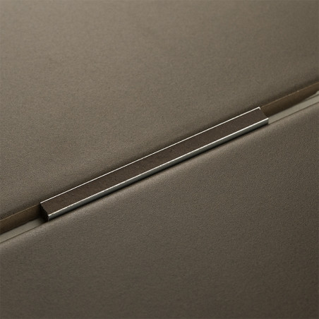 A metal trim rests between two matte gray tiles, forming a precise seam in a modern, minimalistic design.