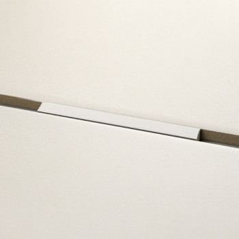 Un carreau blanc rectangulaire repose horizontalement, fixé sur une surface grise avec une fine rainure en dessous, créant une e