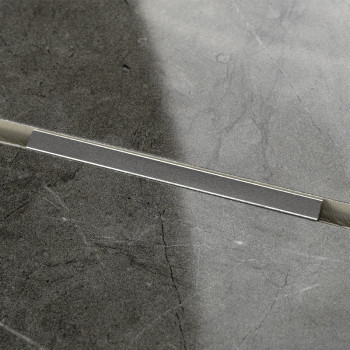 Um ladrilho cinza retangular exibe um padrão linear sutil em um acabamento liso e polido, contra um fundo preto e branco contras
