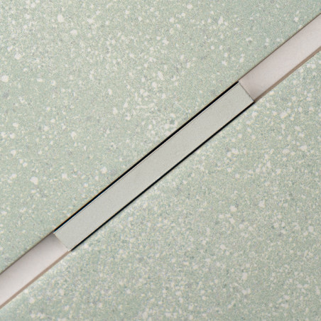 Um ladrilho retangular com um padrão claro salpicado é cruzado diagonalmente por uma faixa fina e elevada, criando um contraste 