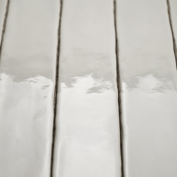 Les carreaux de céramique rectangulaires brillants reflètent la lumière, disposés verticalement avec d'étroites lignes de coulis