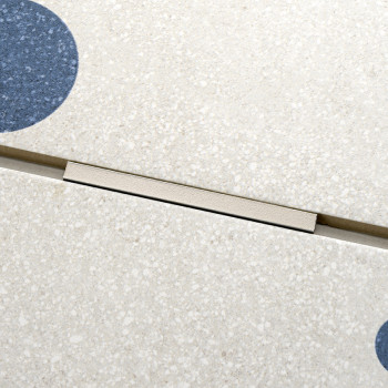 A speckled beige tile features circular indigo patterns and a narrow, metallic groove separating sections, suggesting a modular 