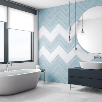 Une salle de bains comprend une baignoire autoportante et une vanité moderne placées contre un mur de carreaux à chevrons bleus 