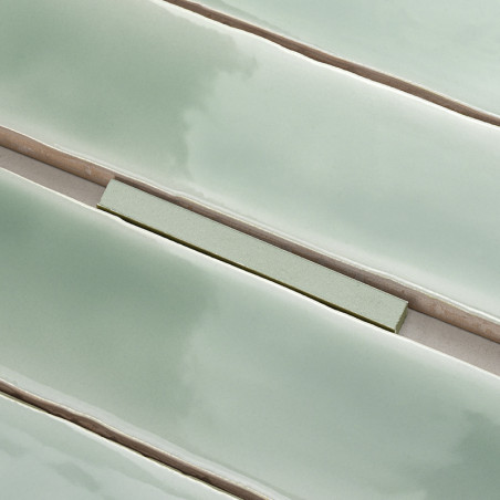 De longs carreaux verts brillants alignés en rangées parallèles, créant une surface lisse et réfléchissante avec des lignes de c