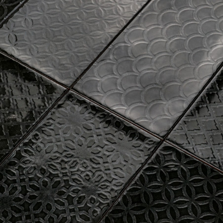 Los azulejos de cerámica negras presentan intrincados patrones geométricos en relieve, que incluyen arcos superpuestos y círculo