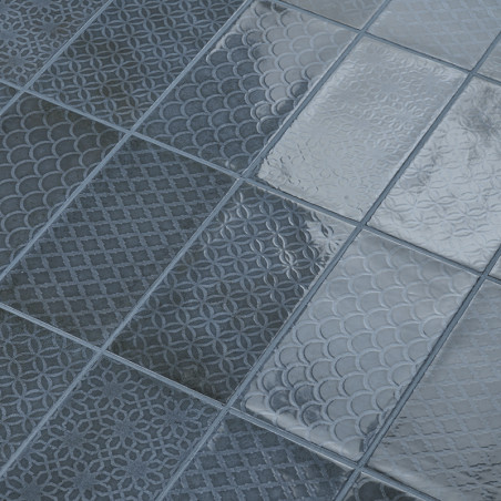Graue Fliesen zeigen komplizierte, sich wiederholende geometrische Muster, die in einem Raster angeordnet sind. Sie reflektieren