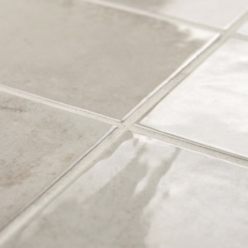 Los azulejos de color beige brillante reflejan la luz, dispuestos en forma de cuadrícula, creando una superficie limpia y modern