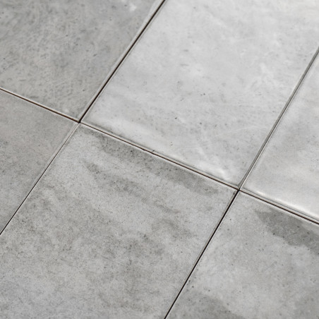 Les carreaux de céramique gris forment un motif de grille, posés à plat et uniformément disposés, mettant en valeur une surface 