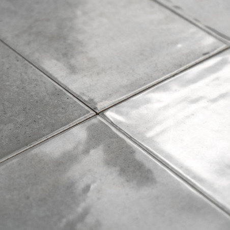 Les carreaux de céramique gris sont plats, réfléchissant la lumière sur leur surface brillante, avec de subtiles variations de t