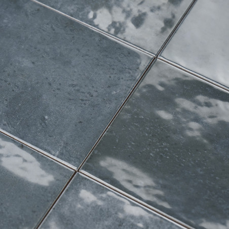 Los azulejos cuadrados muestran un acabado brillante similar al mármol con tonos de remolinos grises y blancos, formando una sup
