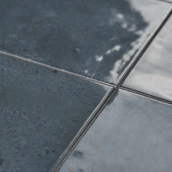 Los azulejos de cerámica oscuros y brillantes reflejan la luz y muestran una superficie ligeramente texturizada con sutiles vari
