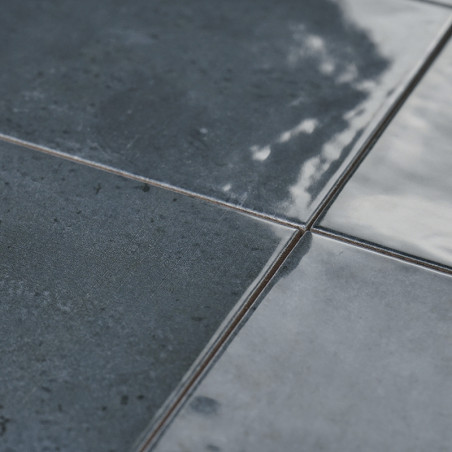 Los azulejos de cerámica oscuros y brillantes reflejan la luz y muestran una superficie ligeramente texturizada con sutiles vari