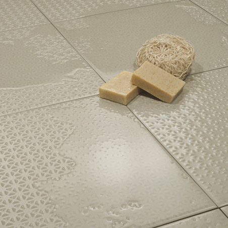 Des carreaux beiges brillants aux motifs complexes en relief sont placés les uns contre les autres, tenant un luffa et deux pain