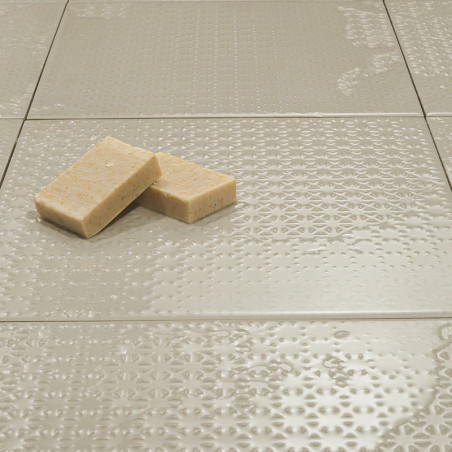 Los azulejos de textura neutra quedan planos y reflejan la luz sutilmente. Dos jabones rectangulares descansan encima, añadiendo