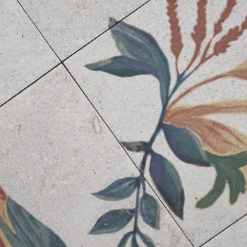 Os ladrilhos cerâmicos apresentam um desenho floral com folhas verdes e flores vermelhas. O padrão se estende por quatro azulejo