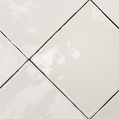 Glossy white square tiles are arranged in a diagonal pattern, creating a smooth, reflective surface with visible grout lines in 