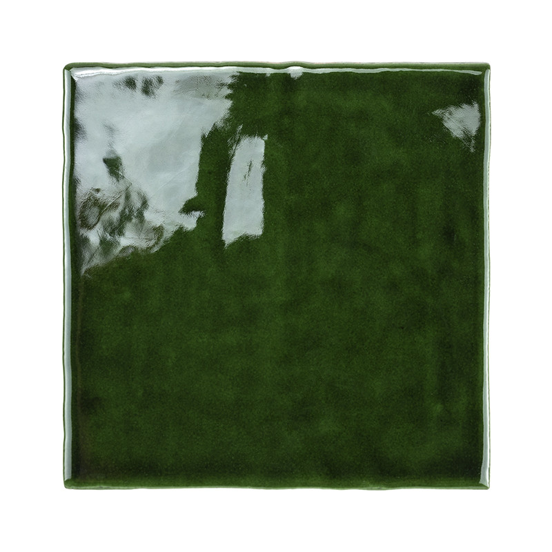 Un azulejo cerámico brillante de color verde oscuro refleja la luz y muestra una superficie lisa y pulida con bordes ligeramente