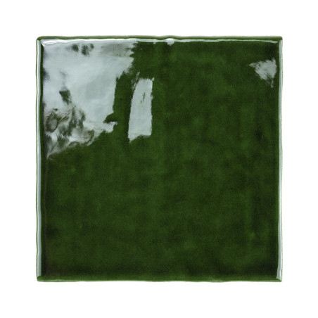 Un azulejo cerámico brillante de color verde oscuro refleja la luz y muestra una superficie lisa y pulida con bordes ligeramente