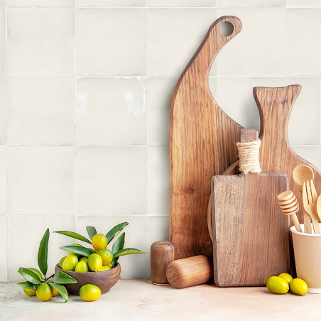 Wooden cutting boards stand upright against a tiled kitchen wall, accompanied by a bowl of green olives and wooden utensils in a