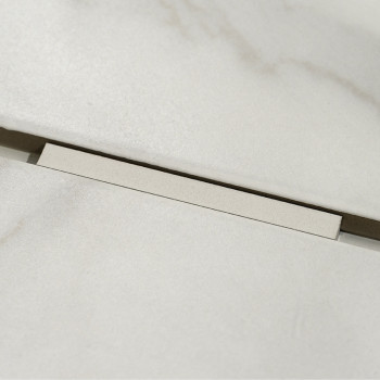 Un carreau rectangulaire beige clair repose légèrement en hauteur sur un fond assorti, révélant un étroit espace sombre en desso