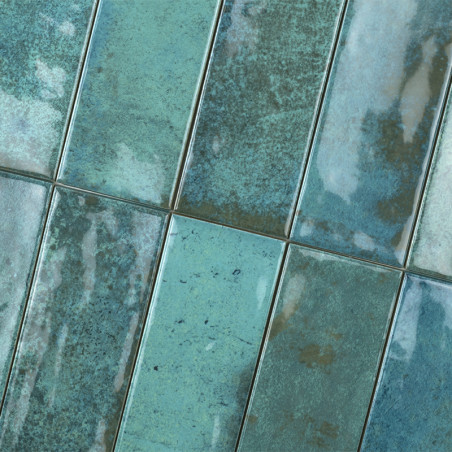 Los azulejos de cerámica rectangulares están dispuestos en un patrón desplazado, mostrando una mezcla moteada de tonos verde azu