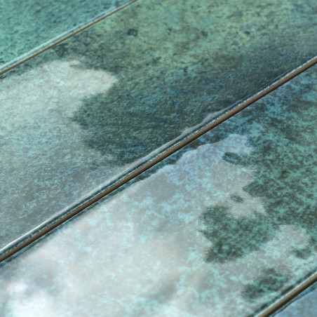 Los azulejos cerámicos rectangulares presentan un acabado brillante y moteado con tonos de verde y azul, dispuestos en un patrón