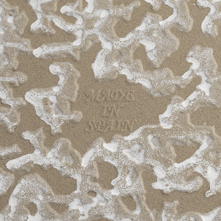 Le carreau présente un motif texturé et ondulé avec un mélange de beige et de blanc. Le texte en relief au centre indique « MADE