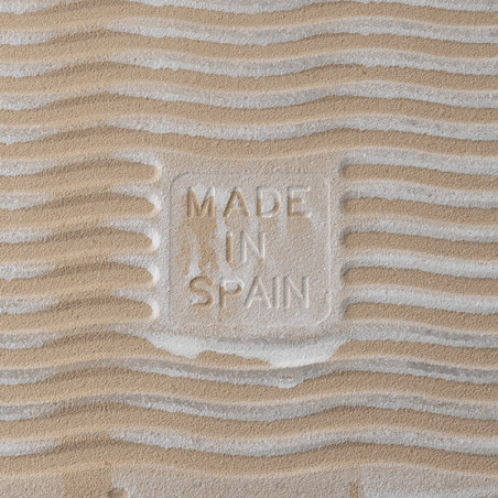 Sand-textured tile with `MADE IN SPAIN` embossed. wavy patterns create a rippled effect, suggesting a beach-like environment.