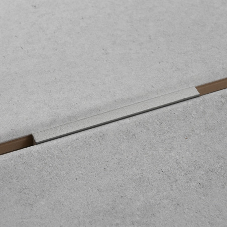 Una losa de hormigón de color gris claro forma una superficie sin costuras con una tira de aluminio estrecha y empotrada que se 