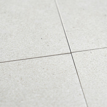Cuatro mosaicos cuadrados de color gris claro se encuentran en un punto central, mostrando una textura fina y una variación de c