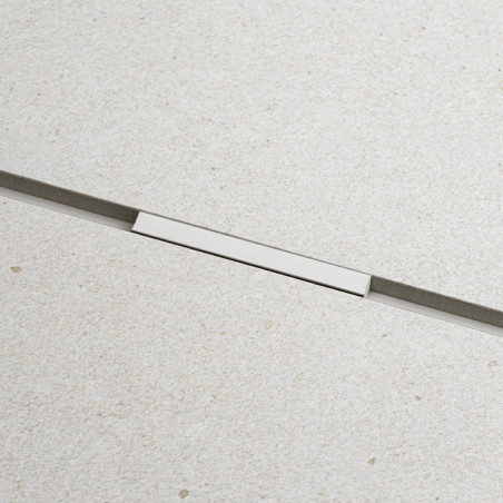 Um ladrilho retangular bege claro e liso com uma textura sutil apresenta uma tira de metal horizontal fina no meio, proporcionan