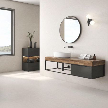 Un miroir rond est suspendu au-dessus d’un lavabo moderne sur une vanité en bois dans une salle de bains minimaliste aux murs be